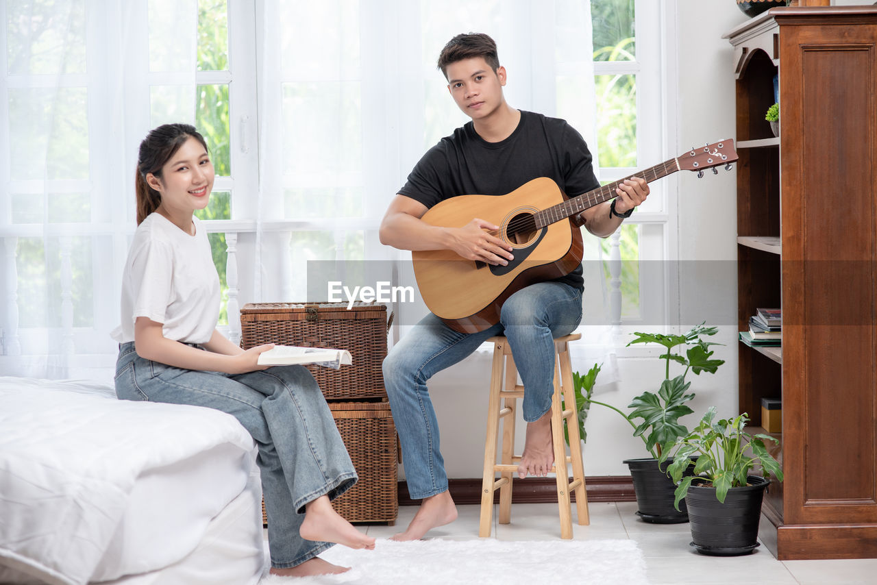 YOUNG MAN PLAYING GUITAR AT HOME