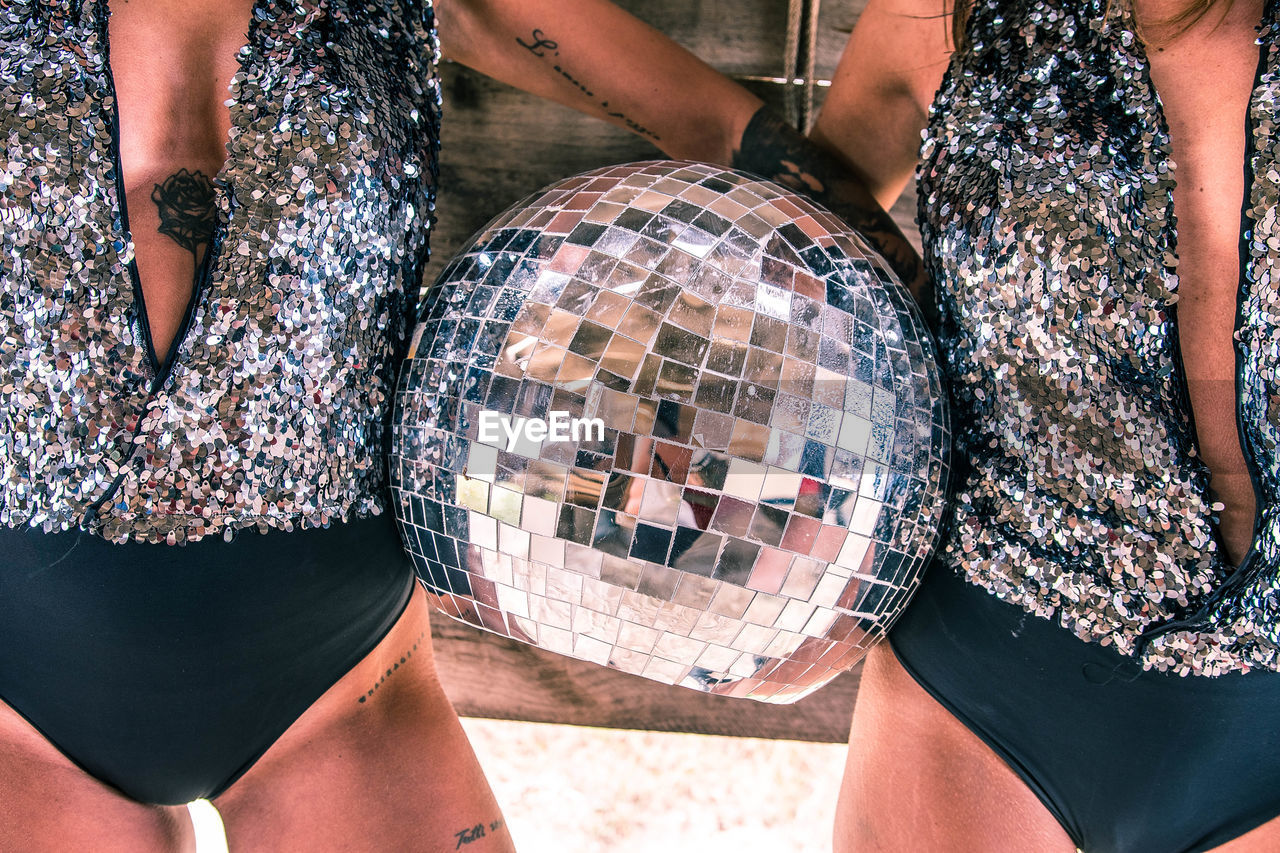 Midsection of female friends holding disco ball
