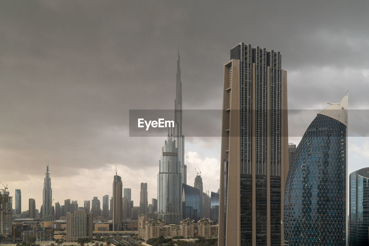 Buildings in city against stormy sky