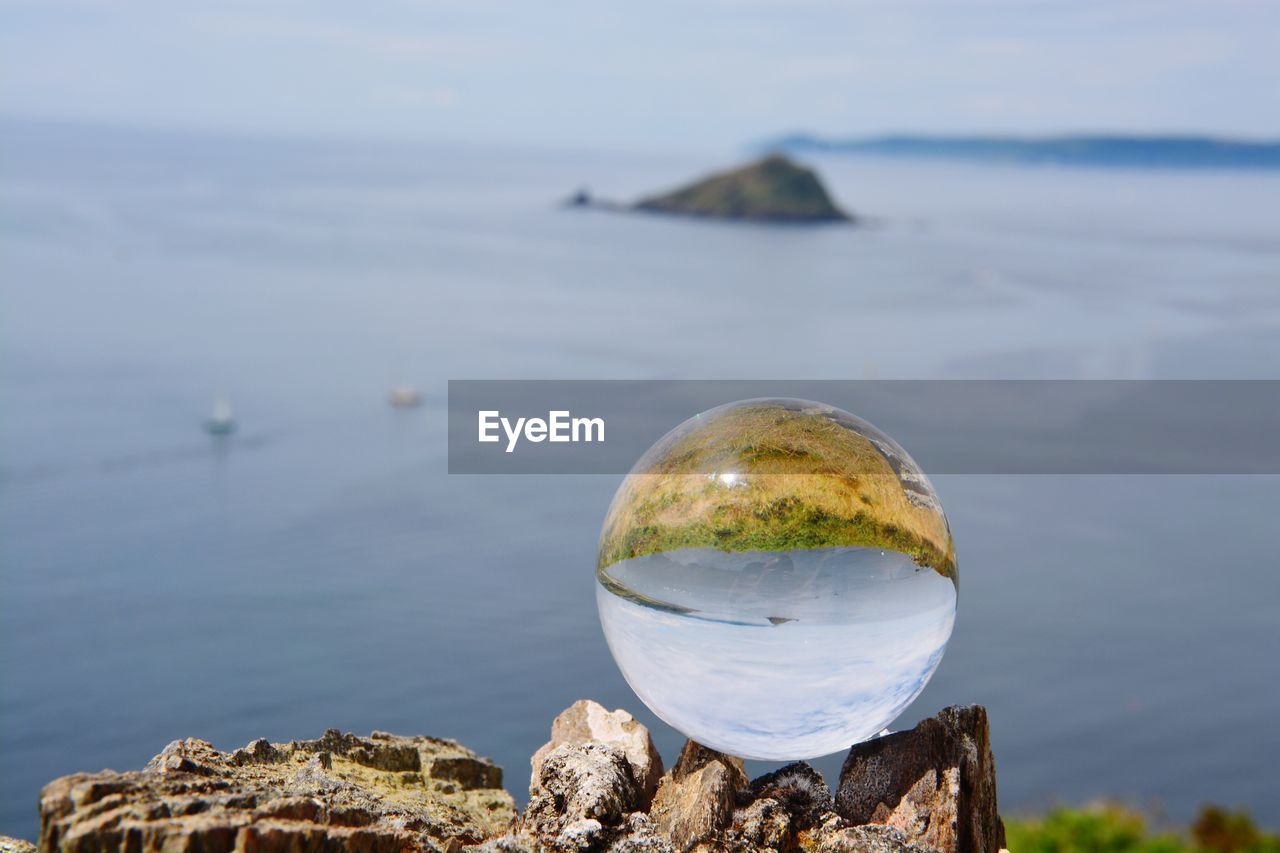 Close-up of crystal ball against calm lake