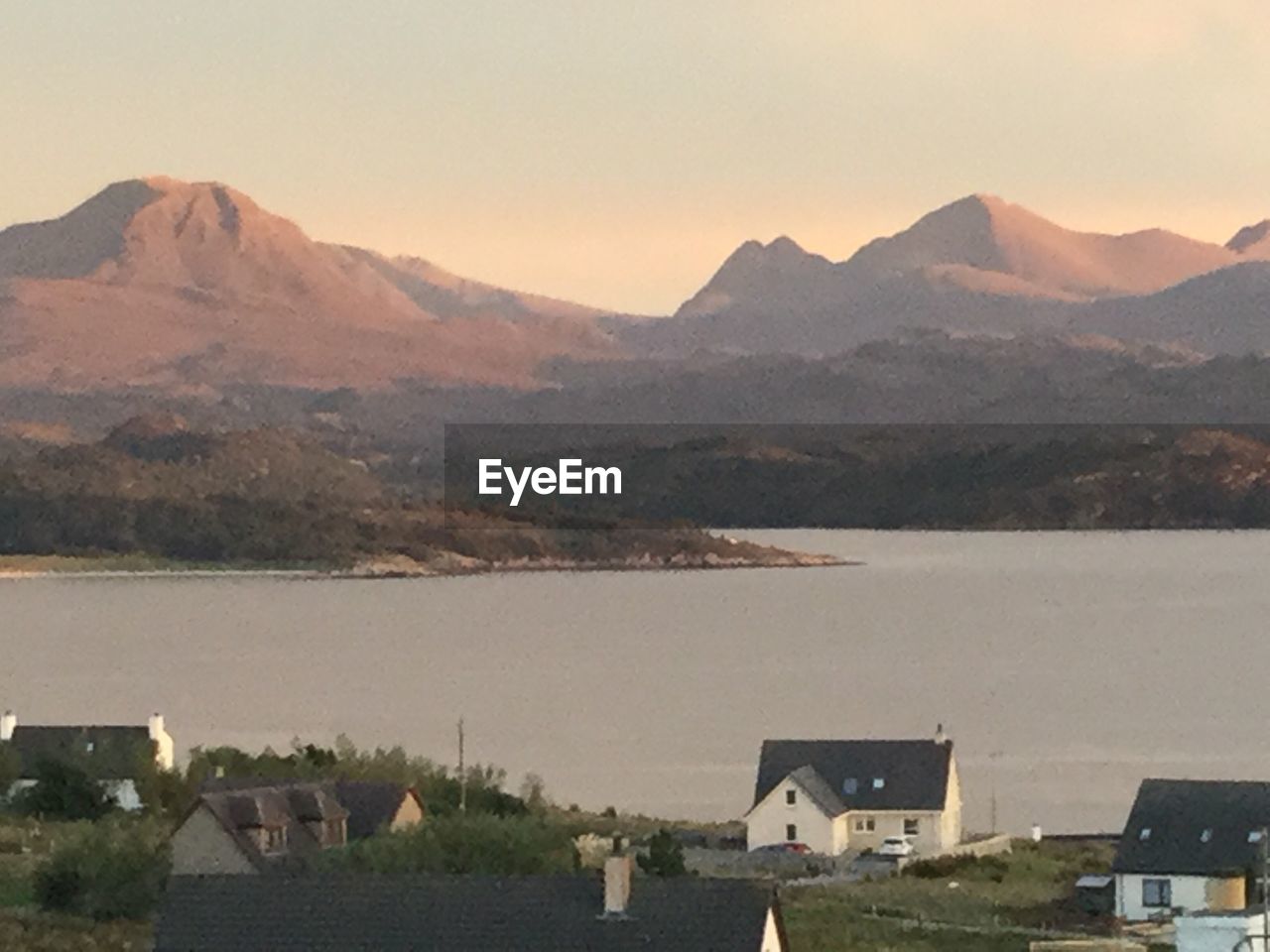 HOUSES BY RIVER AND MOUNTAINS AGAINST SKY IN TOWN