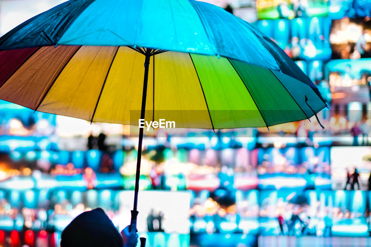 High section of person holding colorful umbrella