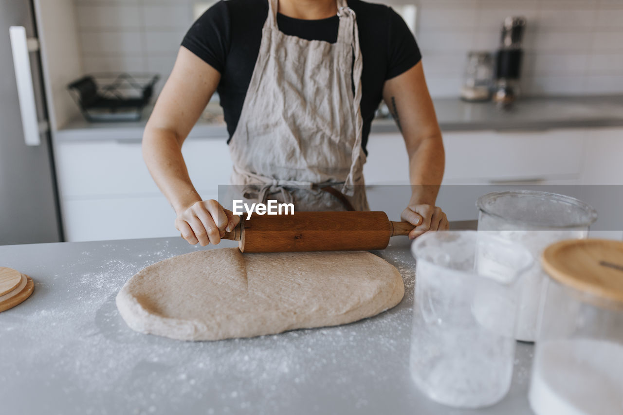 Mid section of woman rolling dough with rolling pin