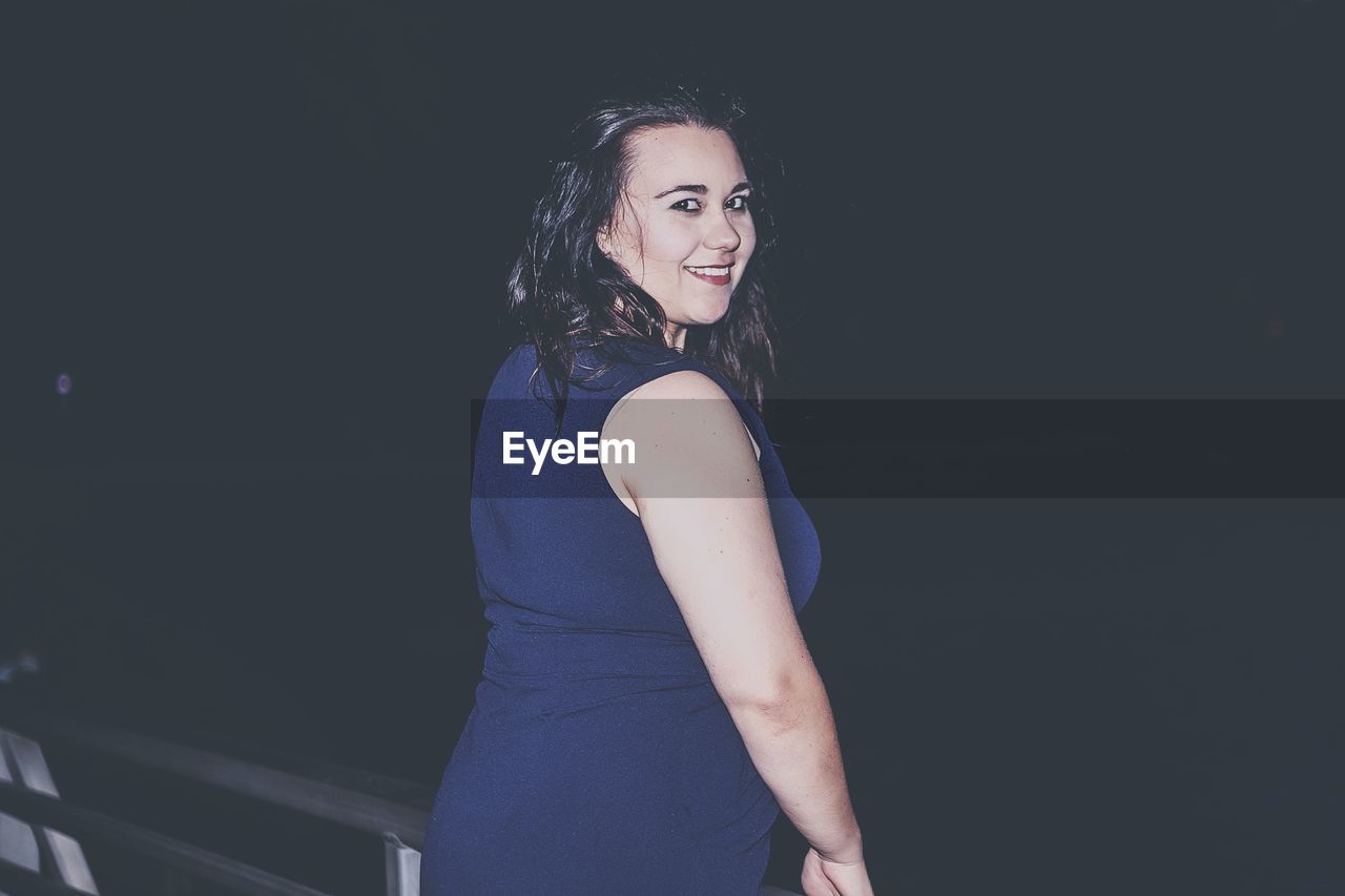 Portrait of smiling woman standing outdoors at night