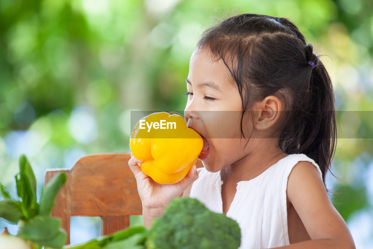 Girl eating yellow bell pepper at home