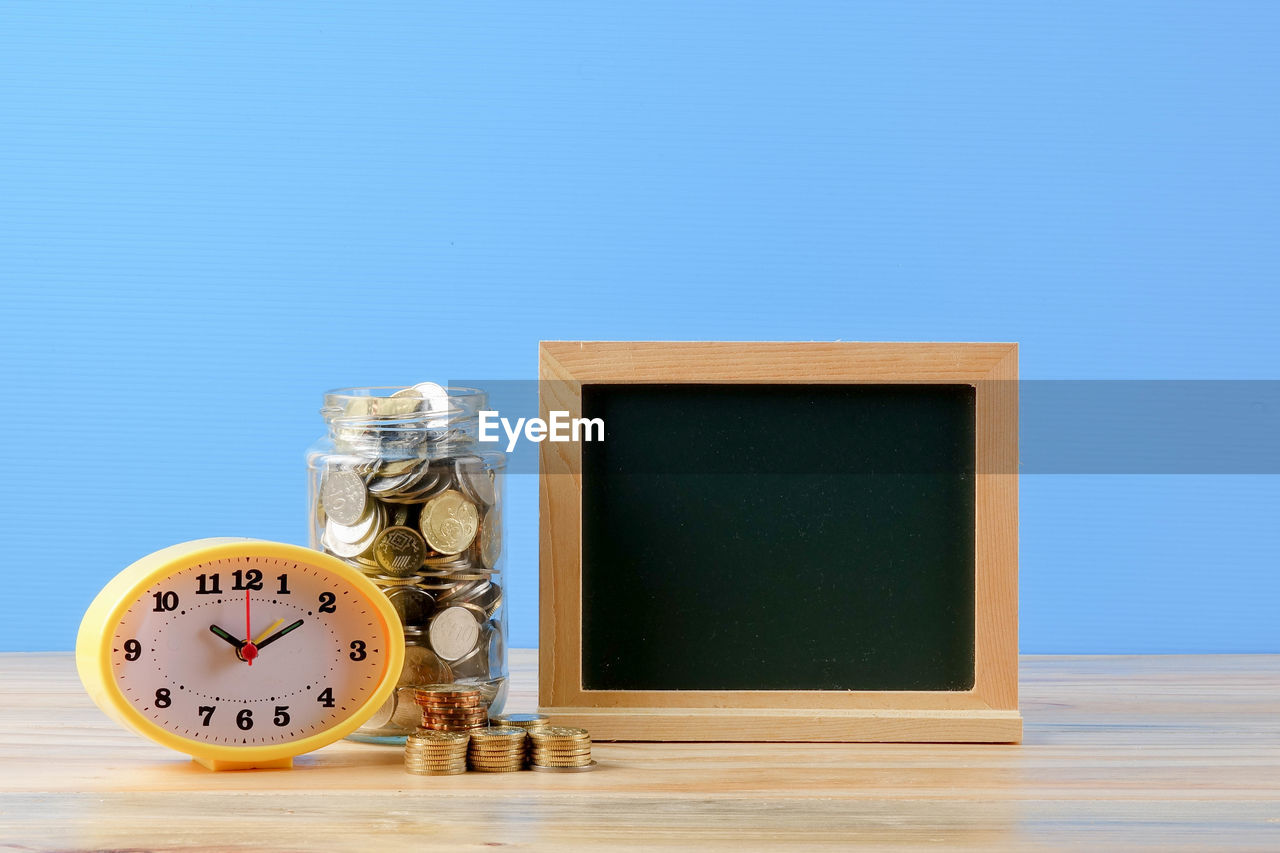 CLOSE-UP OF CLOCK ON TABLE AGAINST WHITE BACKGROUND