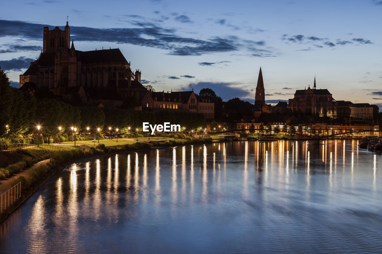 illuminated buildings in city at sunset