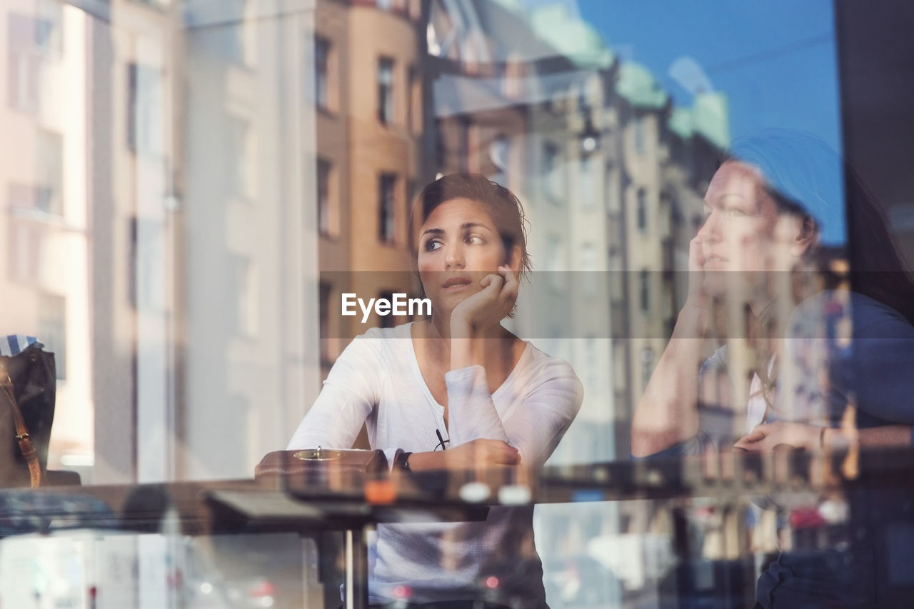 Thoughtful women seen through glass window at cafe