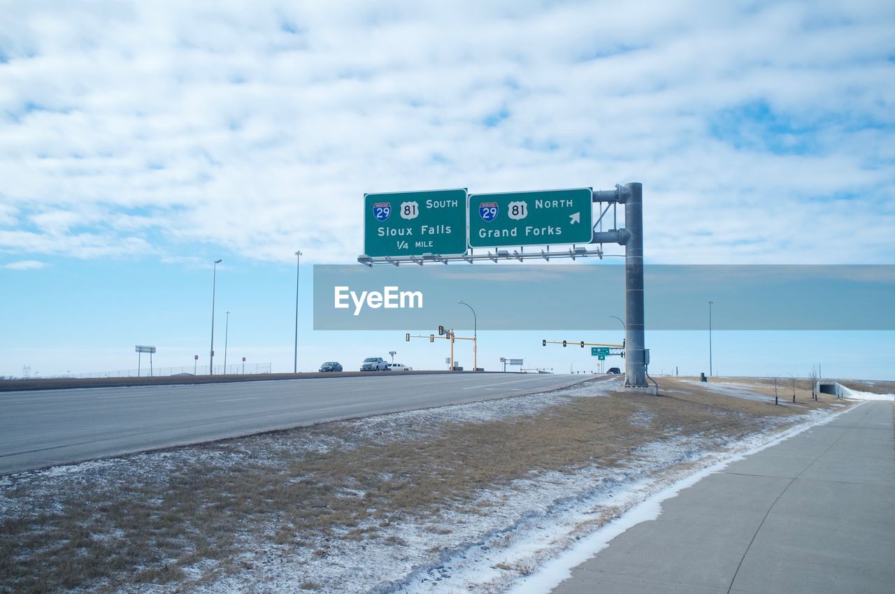 ROAD SIGNS AGAINST CLOUDY SKY