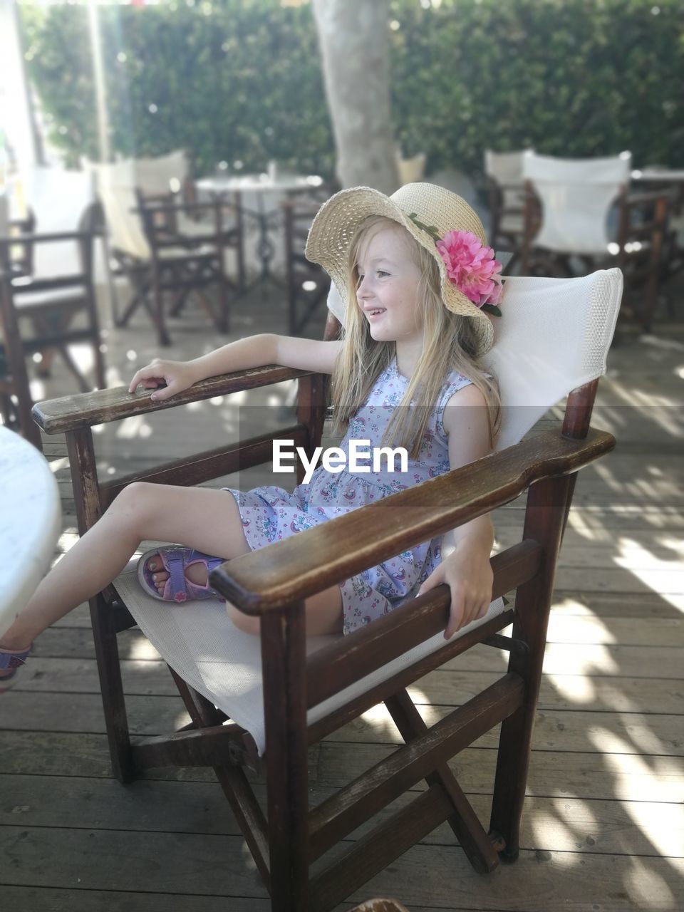 Smiling girl sitting on chair at sidewalk cafe 