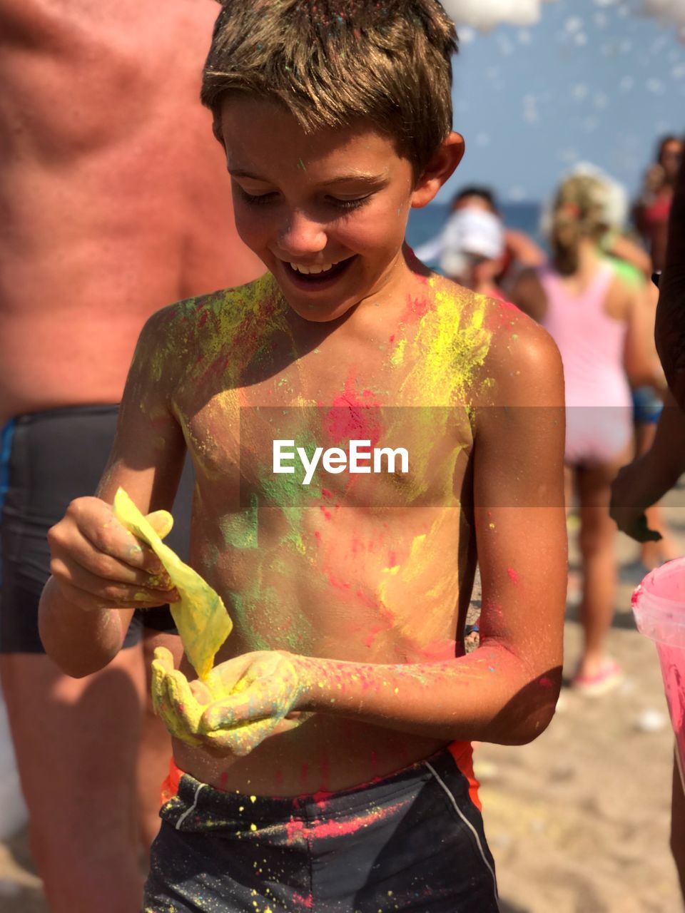 Shirtless boy with powder paint at beach