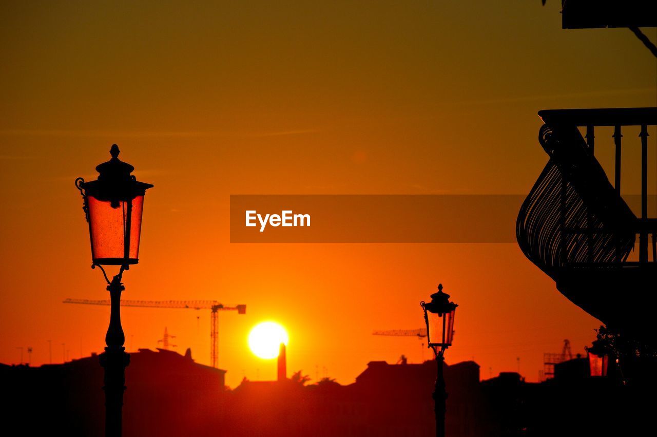 Street lights in city against orange sky