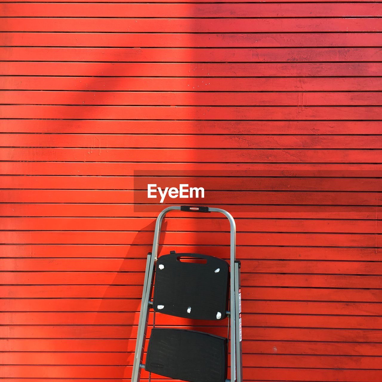 View of ladder next to red wall
