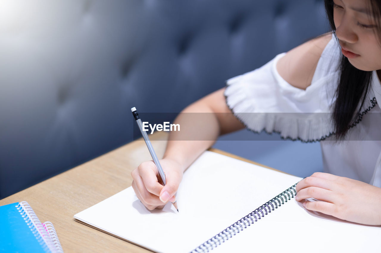 High angle view of girl writing in book