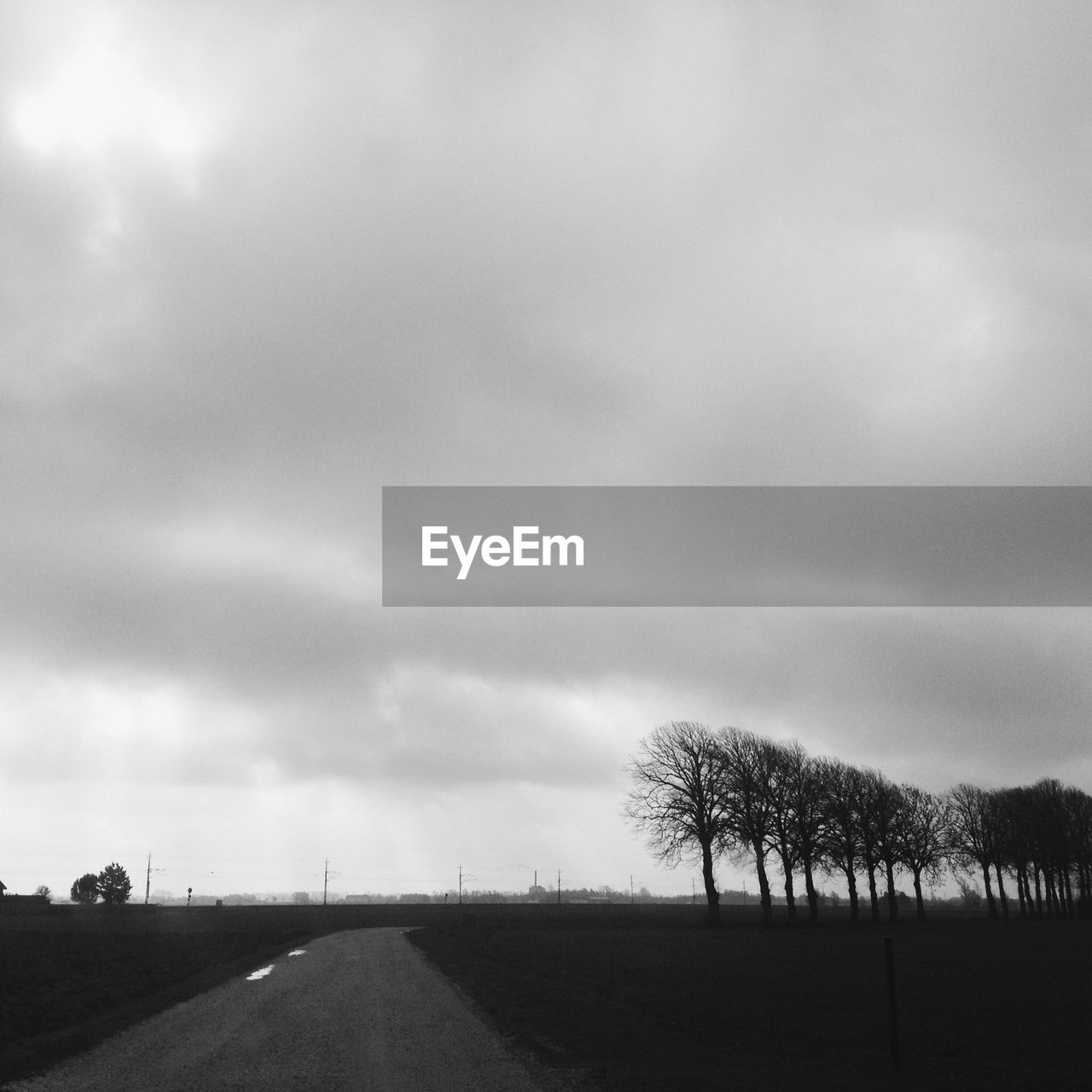 Empty road amidst landscape against cloudy sky