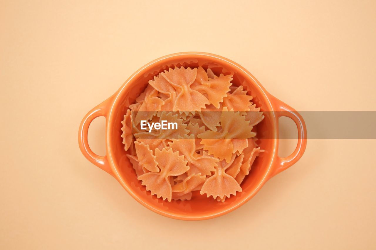 High angle view of pasta in bowl against colored background