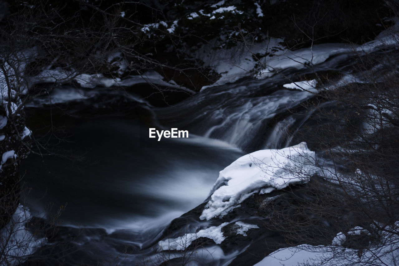 CLOSE-UP OF SNOW ON ROCK BY RIVER