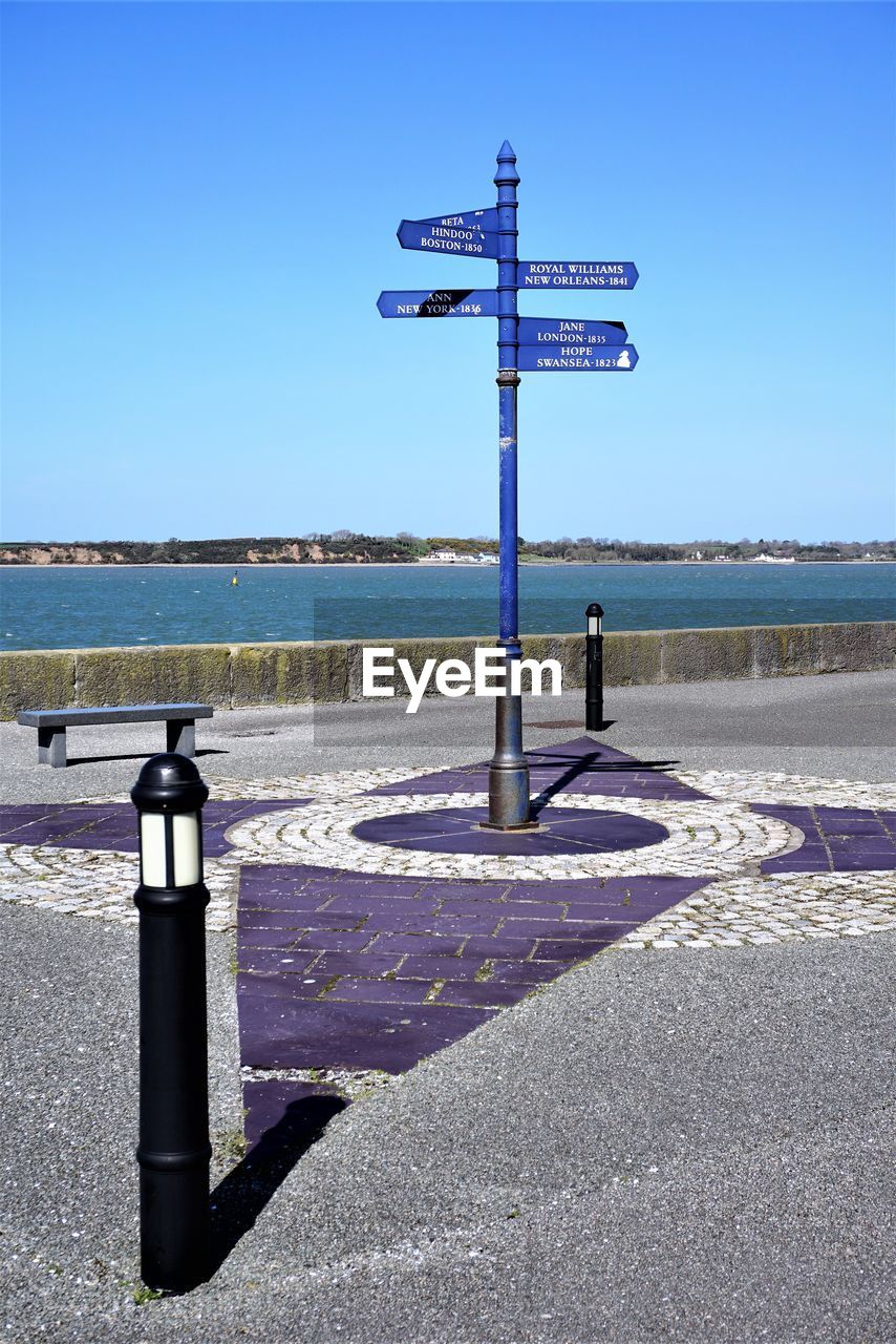 ROAD SIGN BY SEA AGAINST SKY