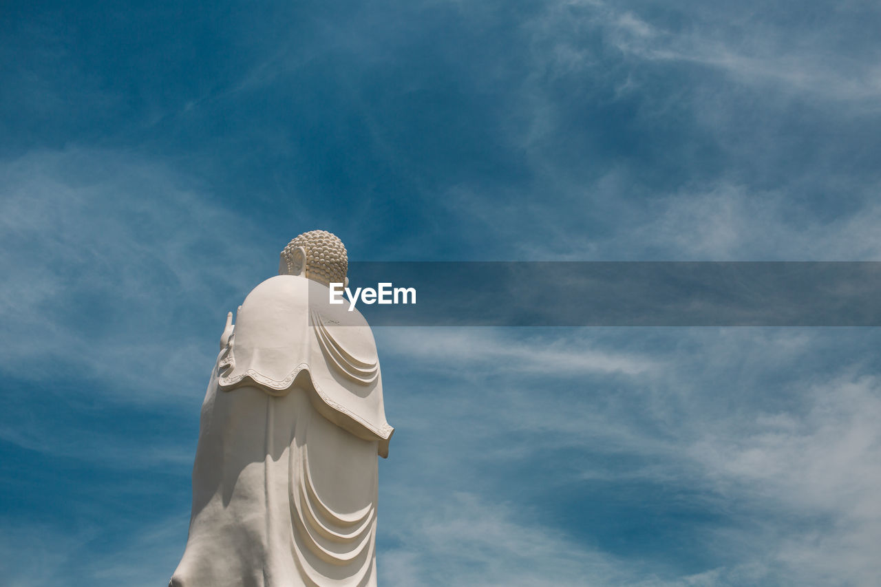 Low angle view of buddha statue against blue sky