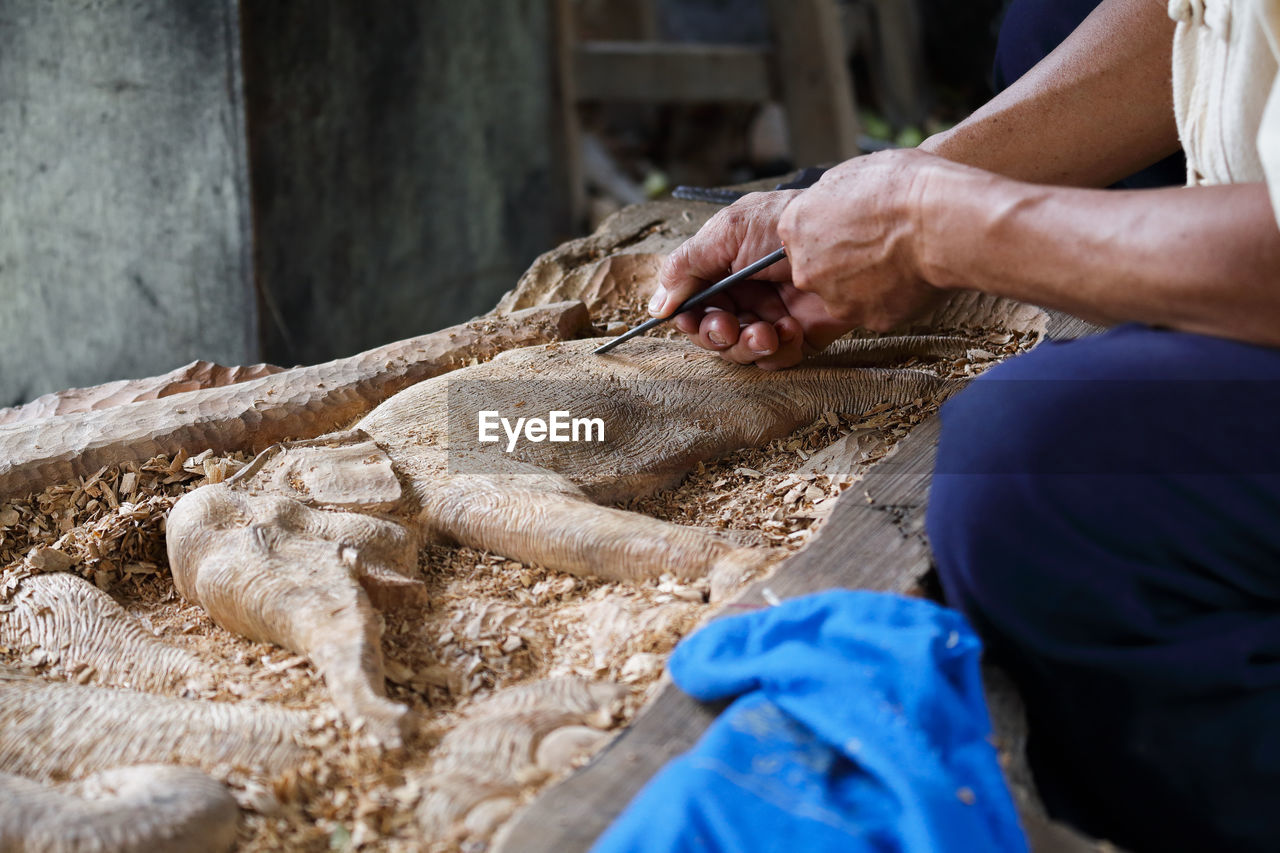 Midsection of man carving elephant on wood at workshop