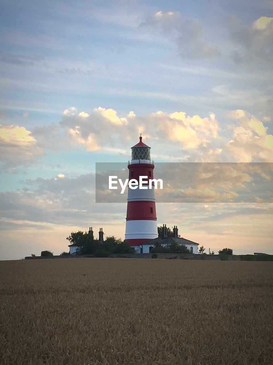 LIGHTHOUSE AMIDST FIELD AGAINST SKY