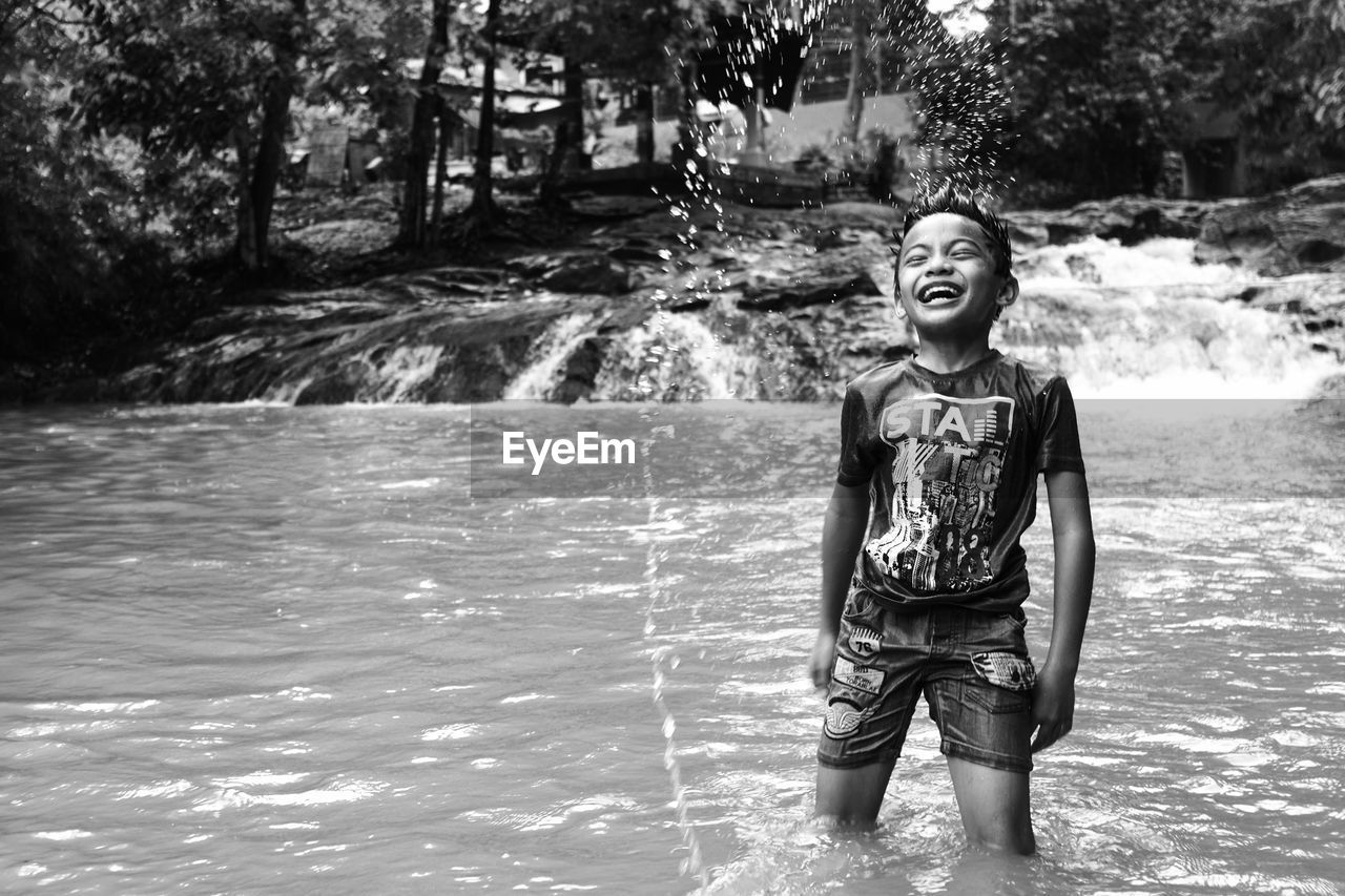 Cheerful boy standing in river