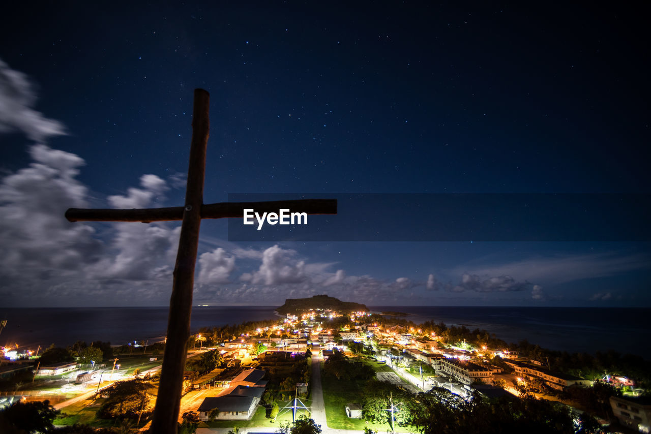 Cross against illuminated city at night