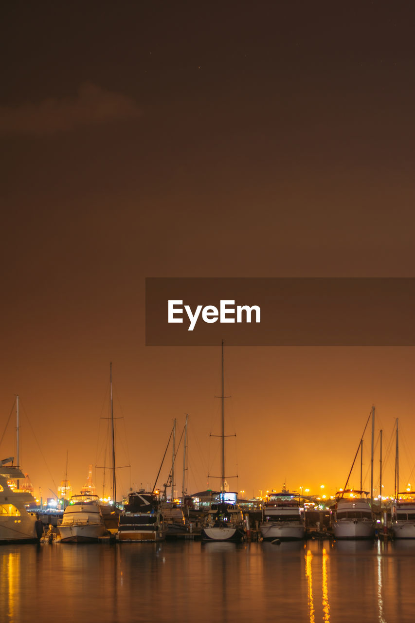 Sailboats in harbor at sunset