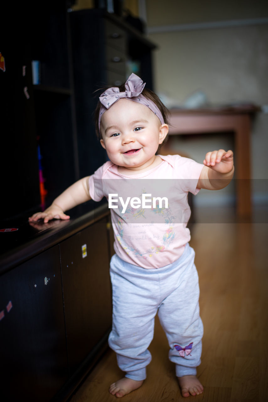 Portrait of cute smiling baby girl wearing headband at home