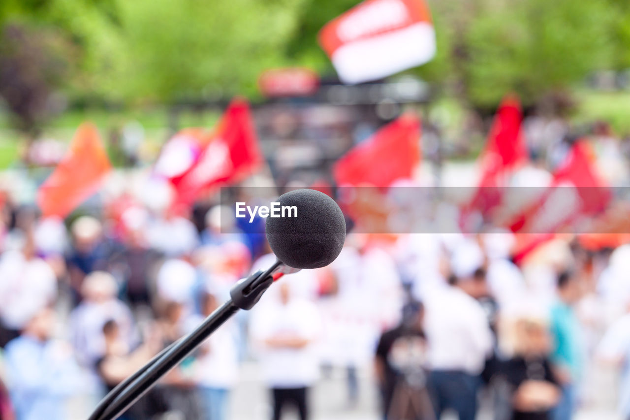 Focus on microphone, blurred group of people at mass protest in the background