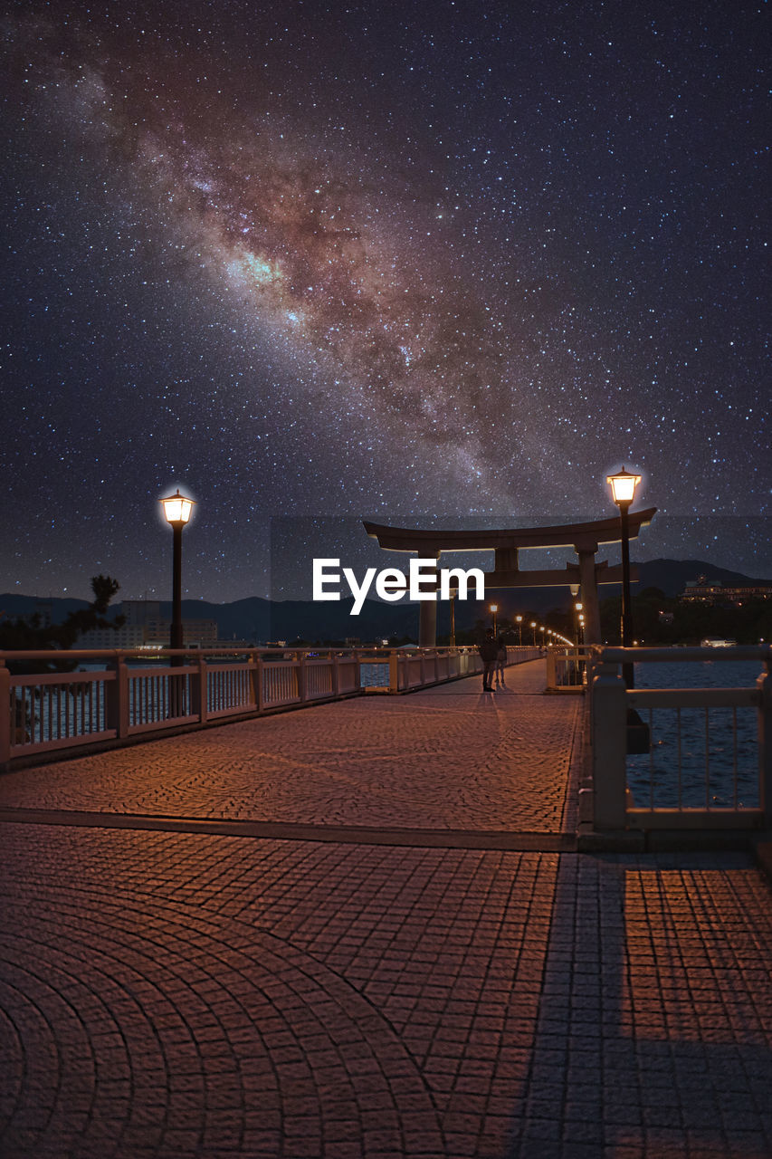 Illuminated pier against sky at night