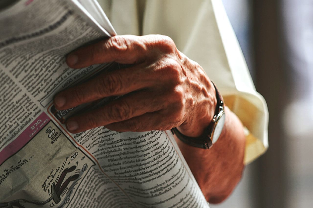 Midsection of man reading newspaper 