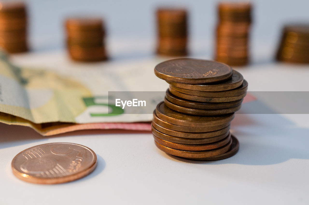 Close-up of coins stack and paper currency on table