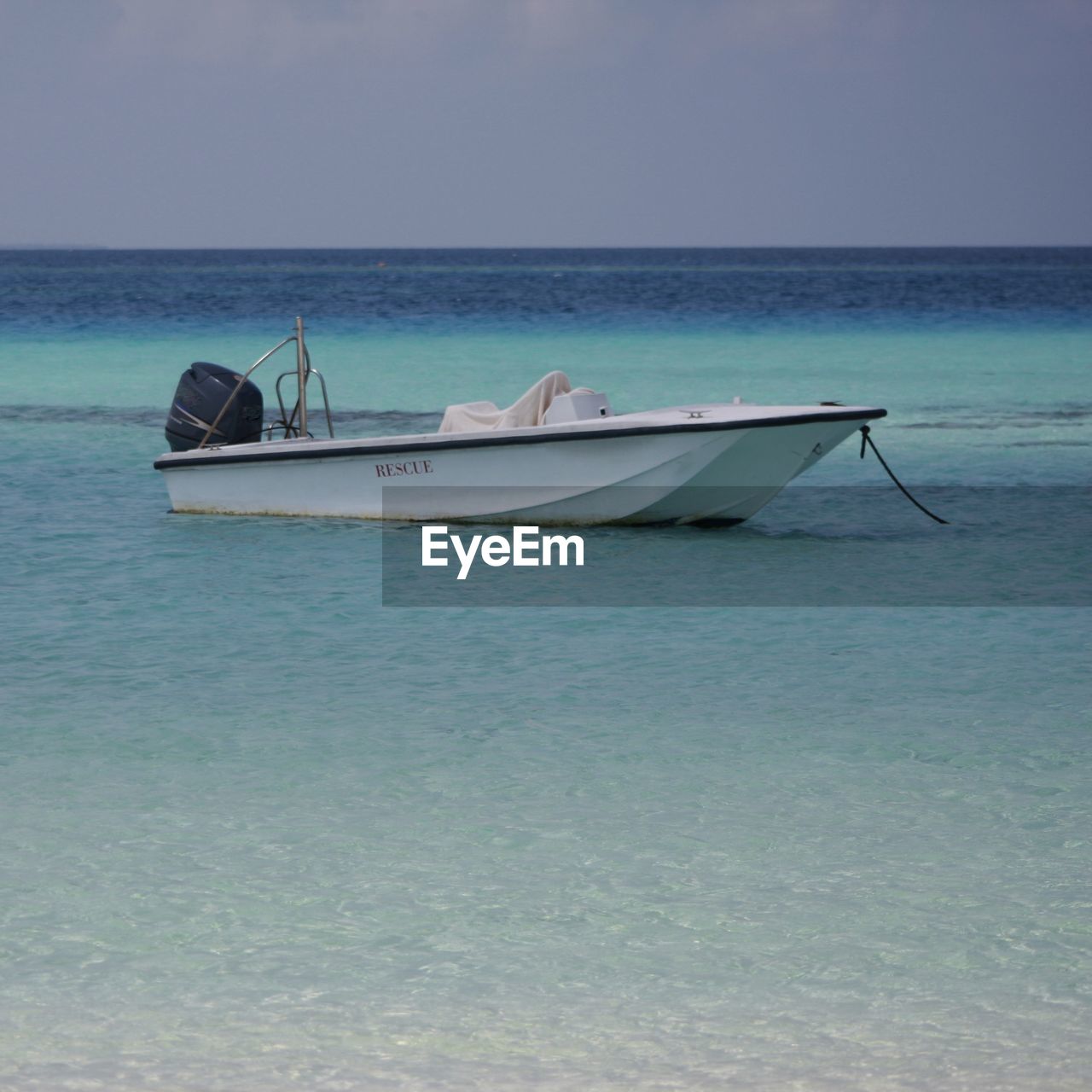 BOAT MOORED IN SEA AGAINST SKY