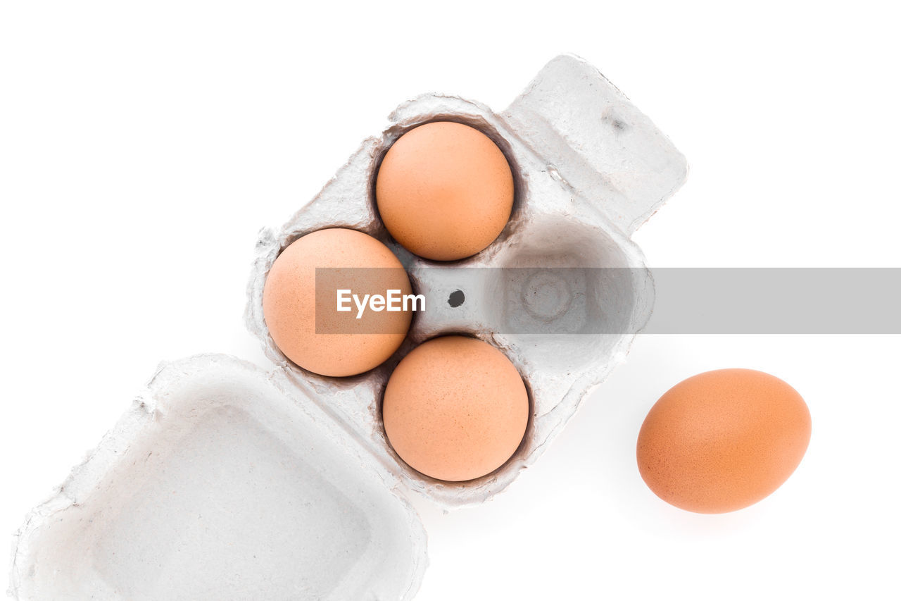Directly above shot of eggs in carton over white background