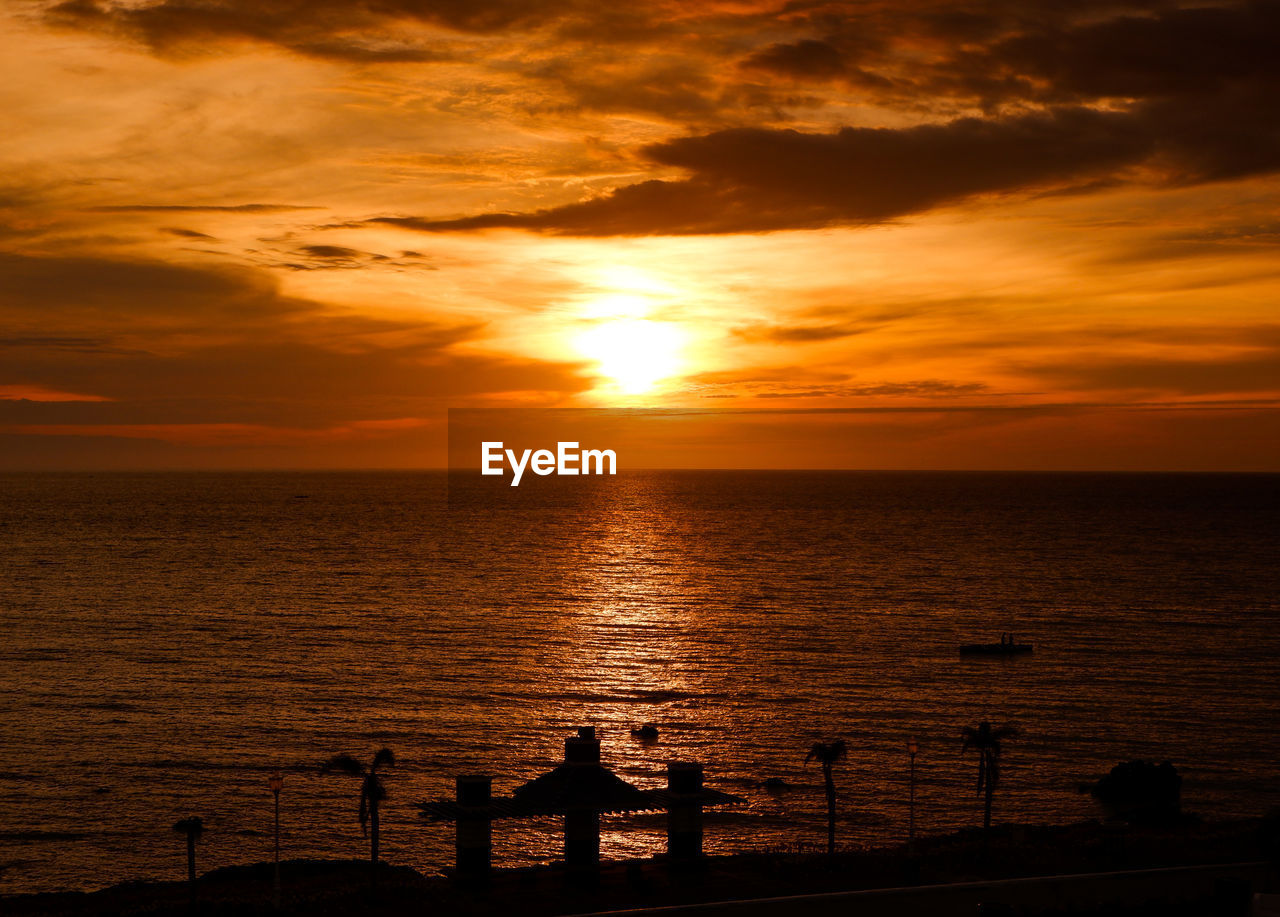 Silhouette of structures at a beach against sky during sunset in the philippines.