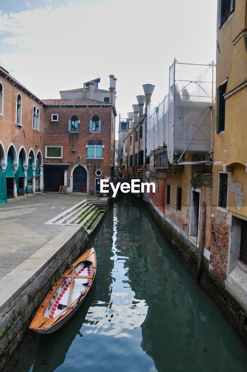 Canal amidst buildings in city against sky