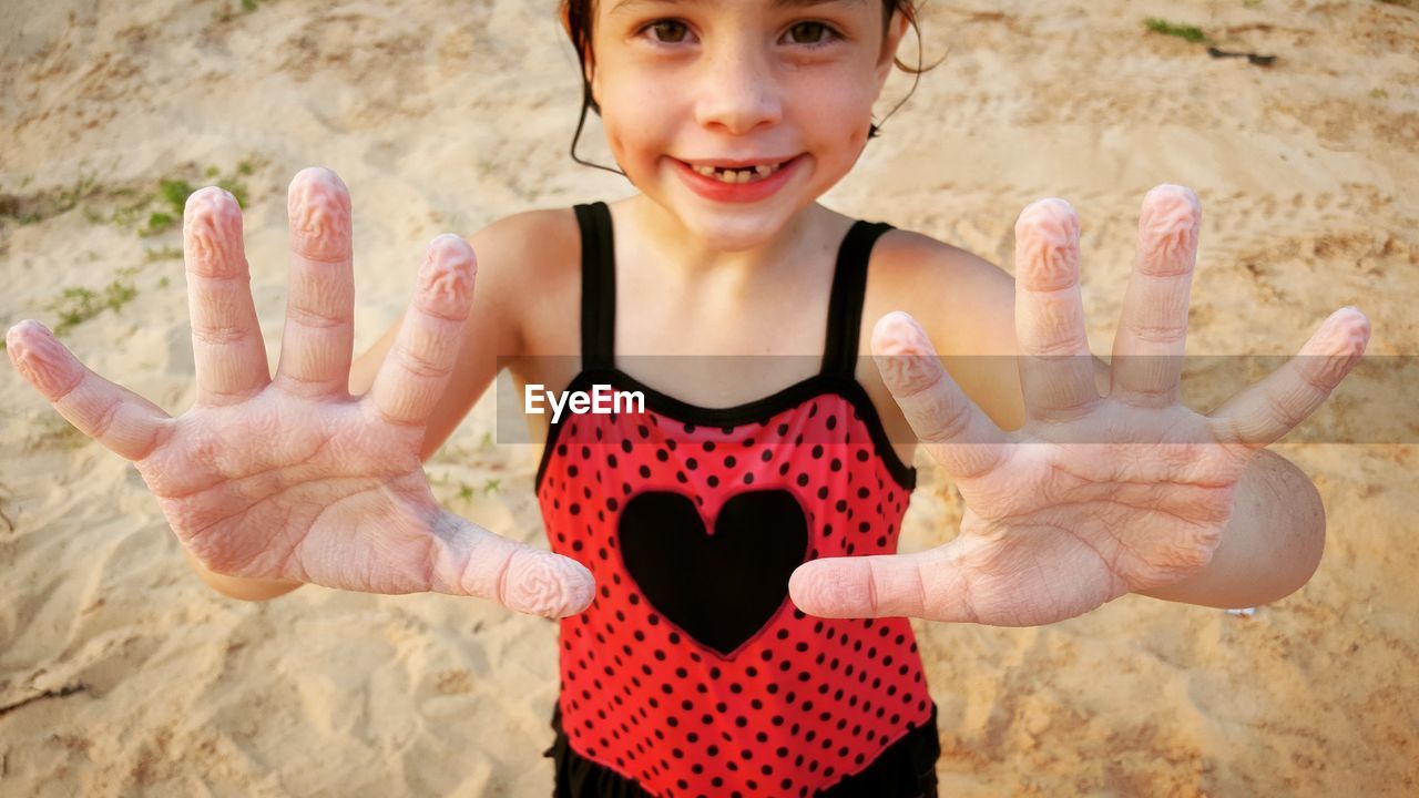 Portrait of girl gesturing while standing at beach