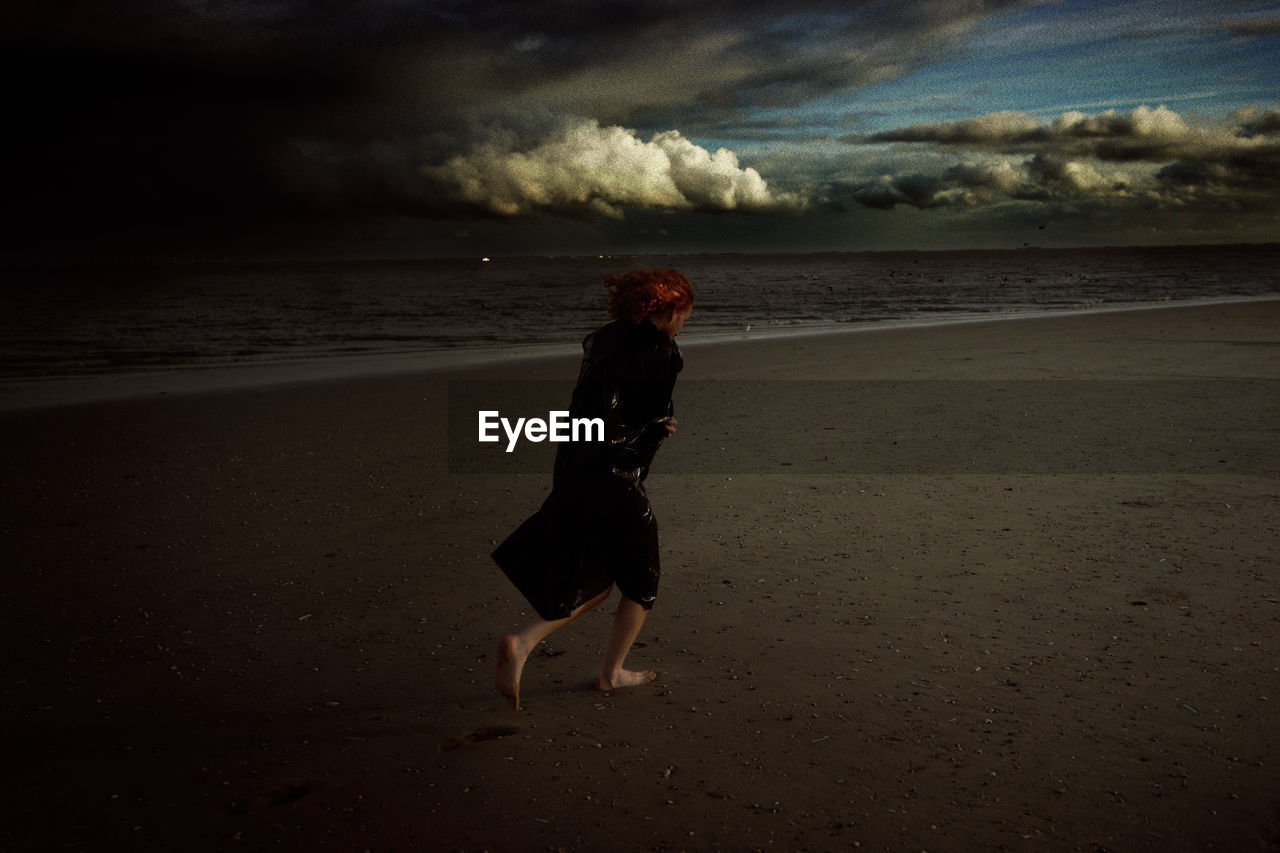 REAR VIEW OF WOMAN WALKING ON BEACH