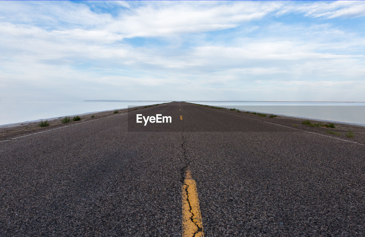 SURFACE LEVEL VIEW OF ROAD AGAINST CLOUDY SKY