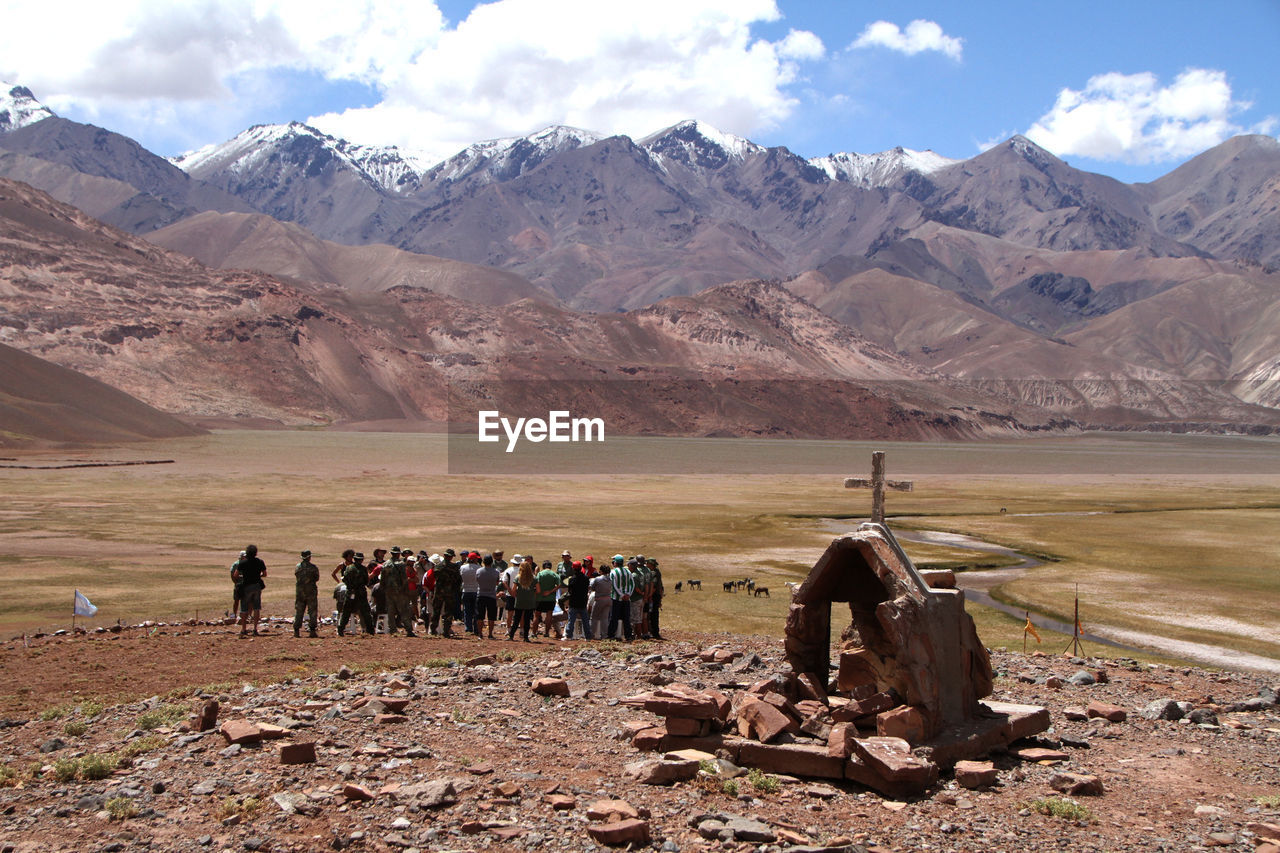 People on field by mountains against sky