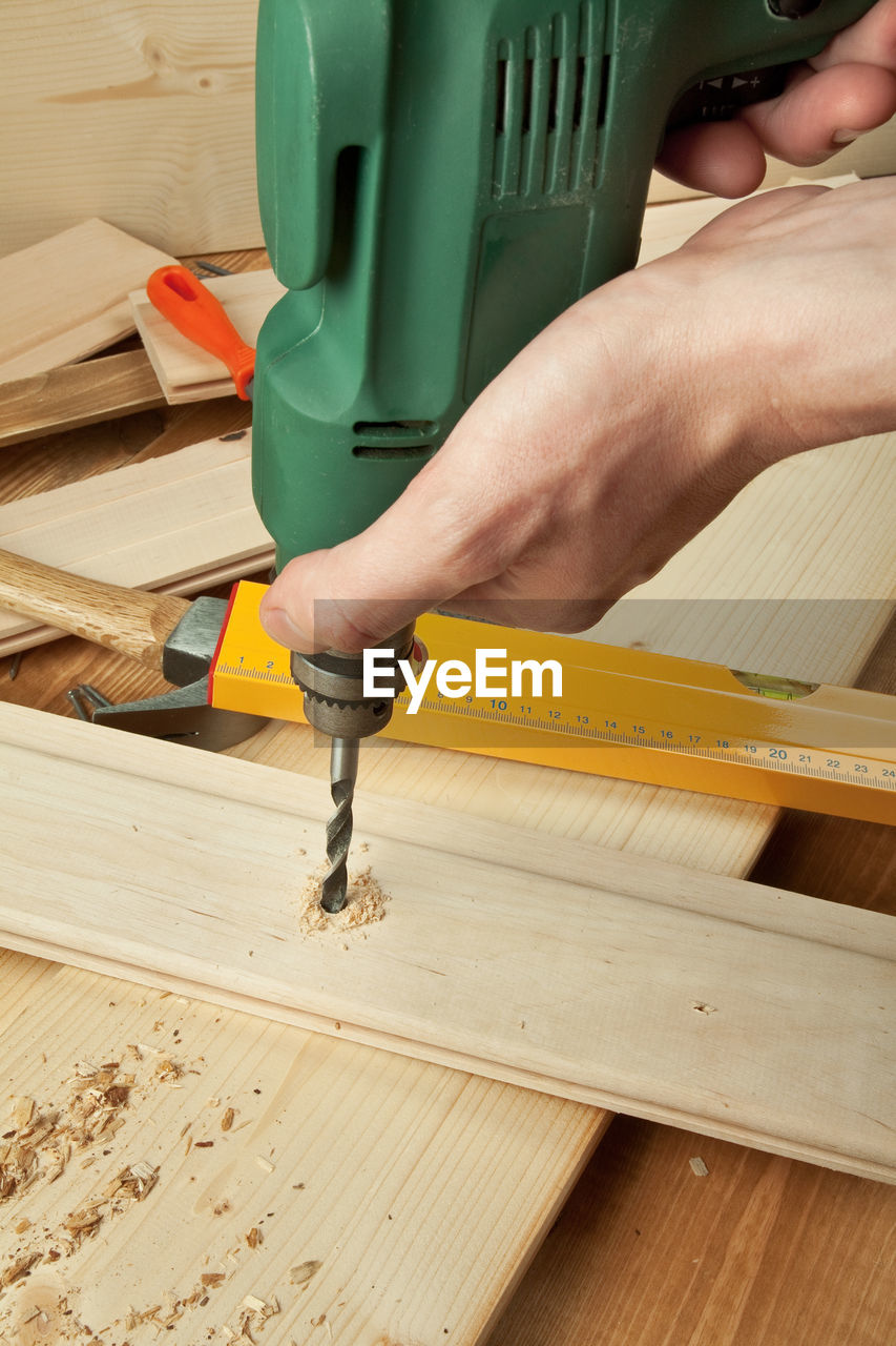 Close-up of craftsperson drilling wooden plank