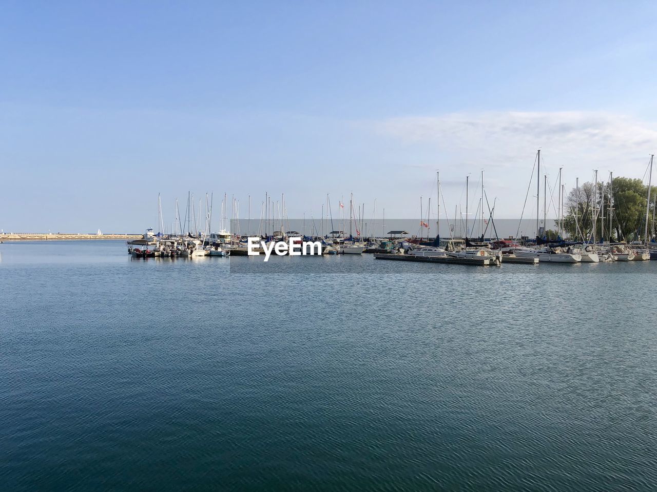 SAILBOATS MOORED IN SEA AGAINST SKY