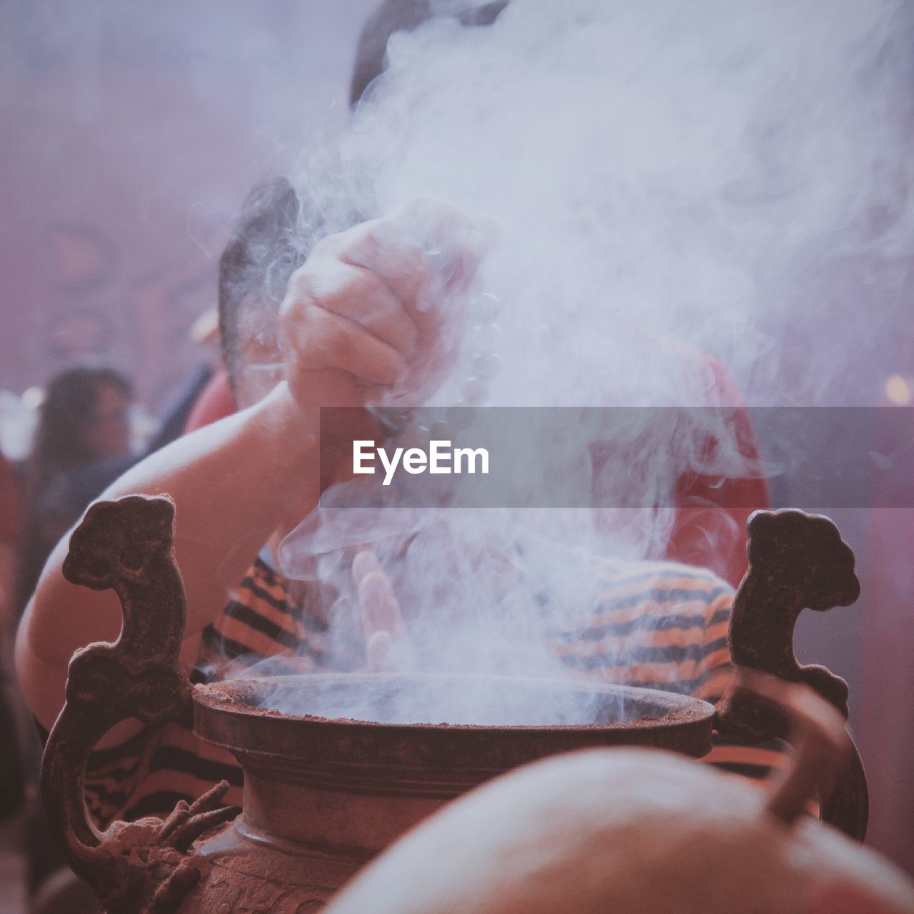 Close-up of boy praying at temple amidst smoke