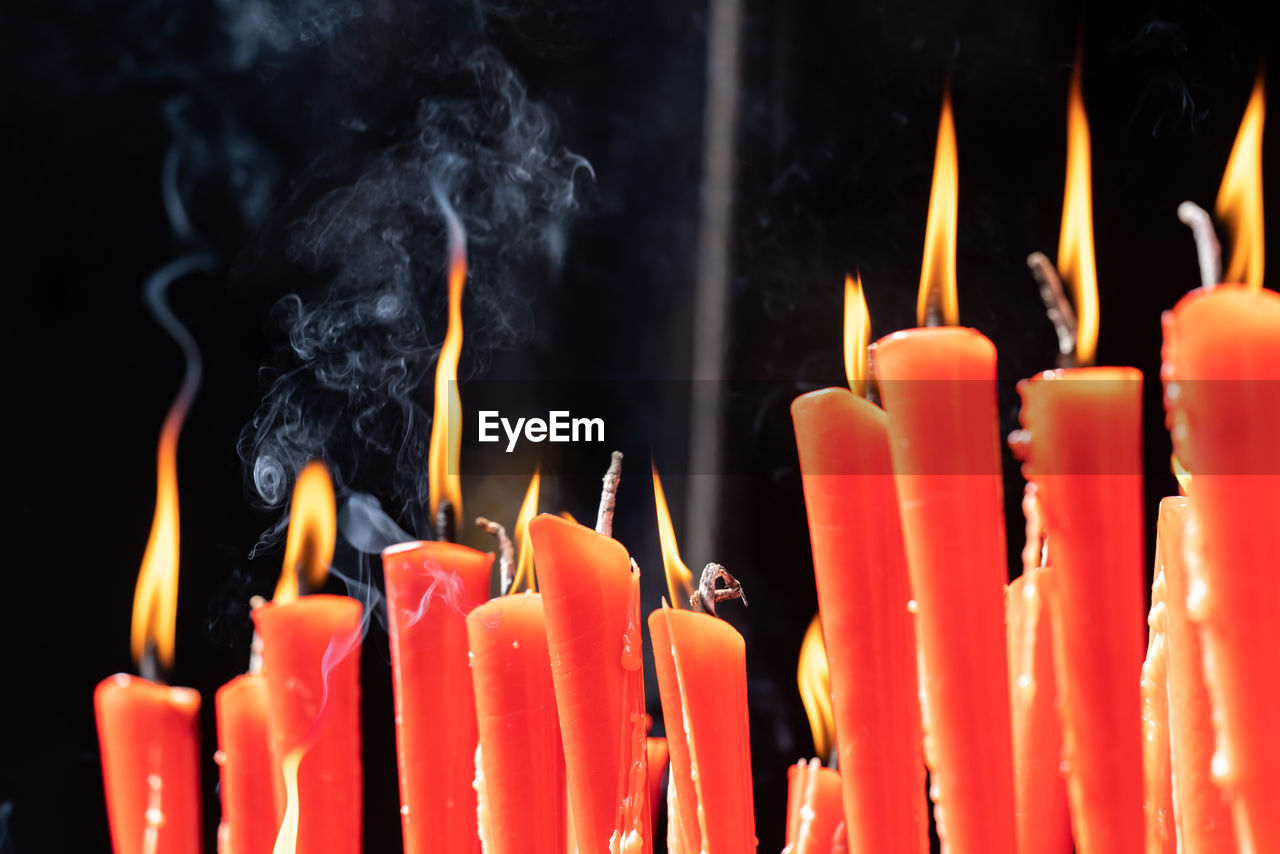 Rows of burning red candles are used in religious prayers