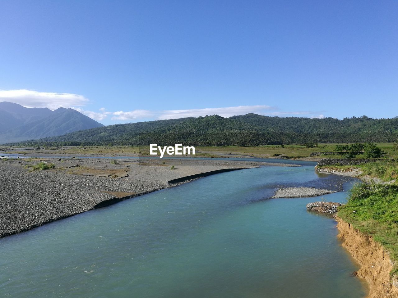 Scenic view of lake by mountains against blue sky