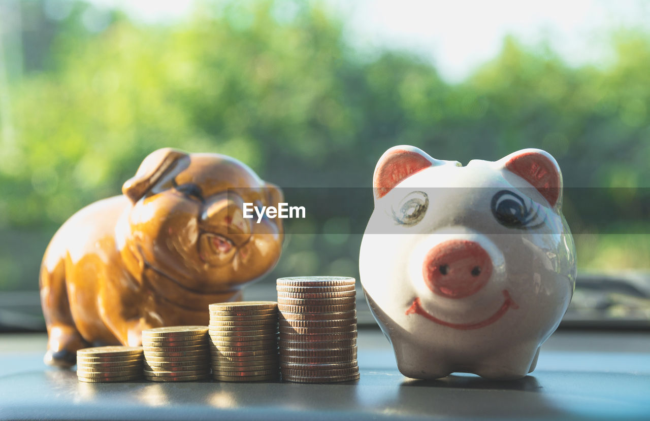 Stacked coins and piggy banks on table