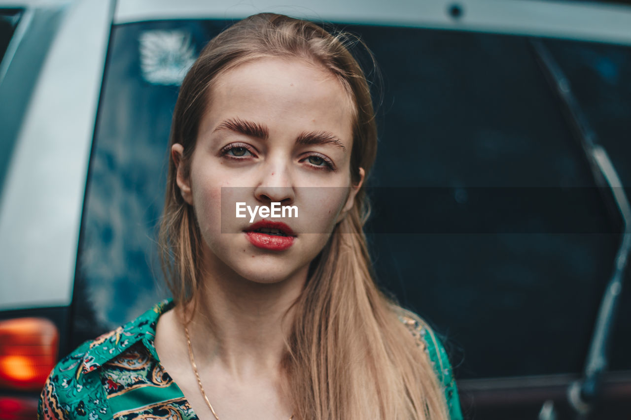 Portrait of beautiful woman standing against car