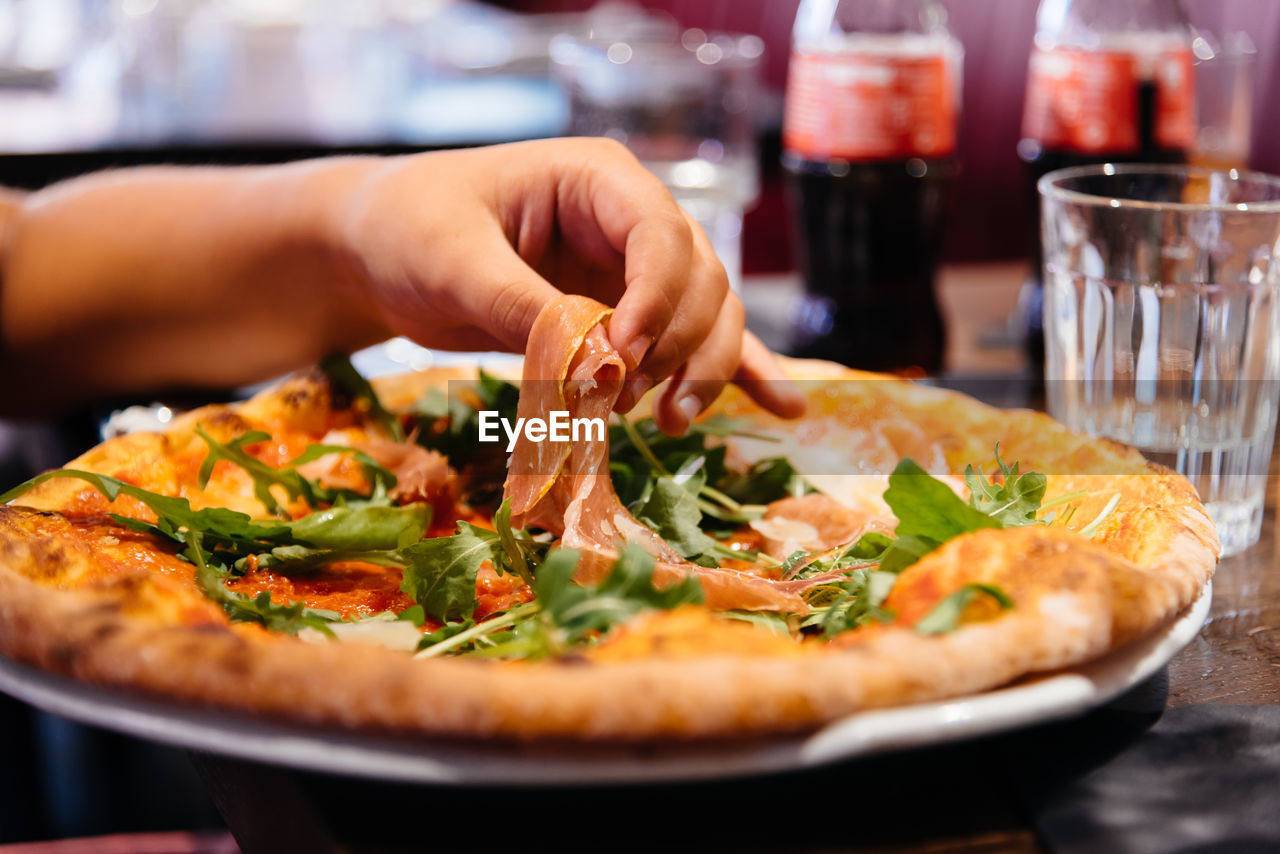 Cropped hand of woman having pizza on table