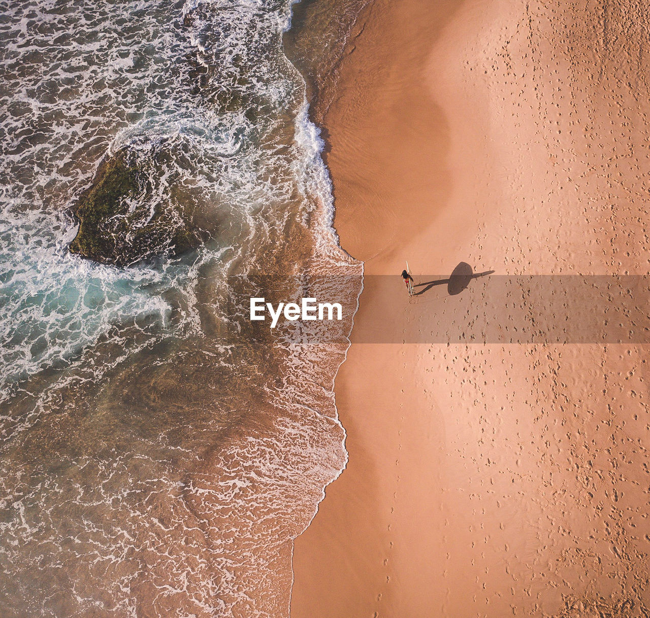 High angle view of woman carrying surfboard on shore at beach